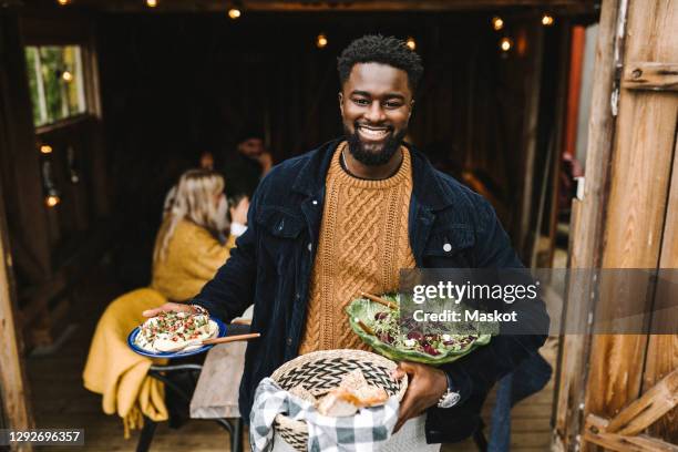 portrait of smiling man with food standing at doorway during party - sitting at table looking at camera stock pictures, royalty-free photos & images
