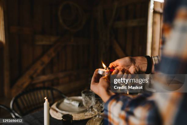 cropped image of woman igniting candle by dining table during social gathering - tea light stock pictures, royalty-free photos & images