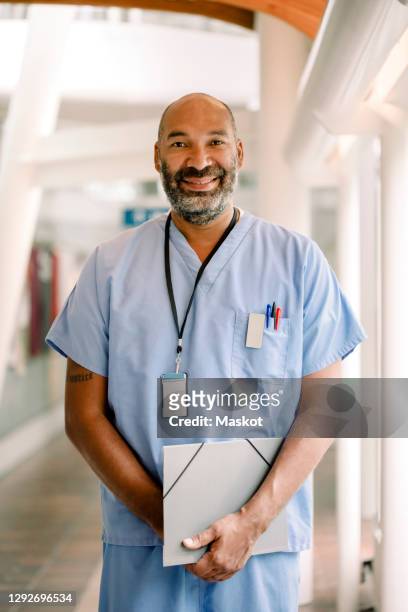 portrait of smiling male nurse standing in hospital corridor - arts culture and entertainment stockfoto's en -beelden