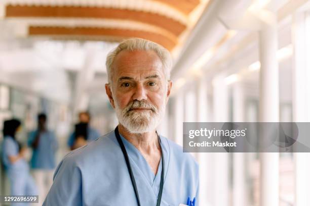 portrait of senior male nurse in hospital corridor - mid adult men stock pictures, royalty-free photos & images