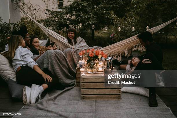 smiling friends enjoying at social gathering in yard during sunset - hanging in garden photos et images de collection