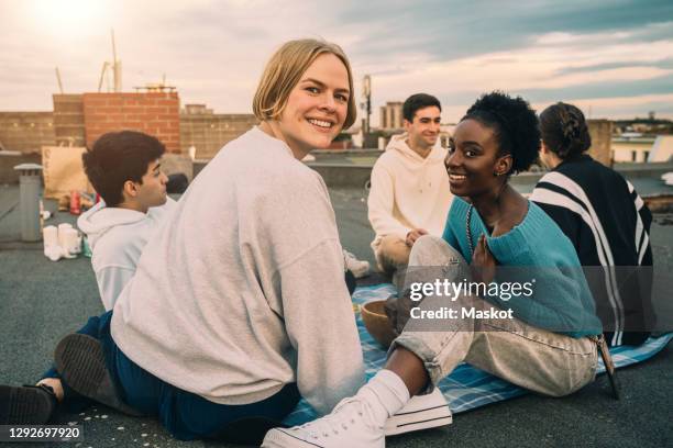 portrait of female friends enjoying on building terrace during sunset - friends city stock-fotos und bilder