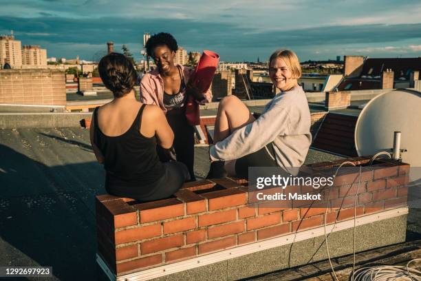 portrait of smiling female friends after yoga on rooftop during sunrise - yoga germany stock pictures, royalty-free photos & images