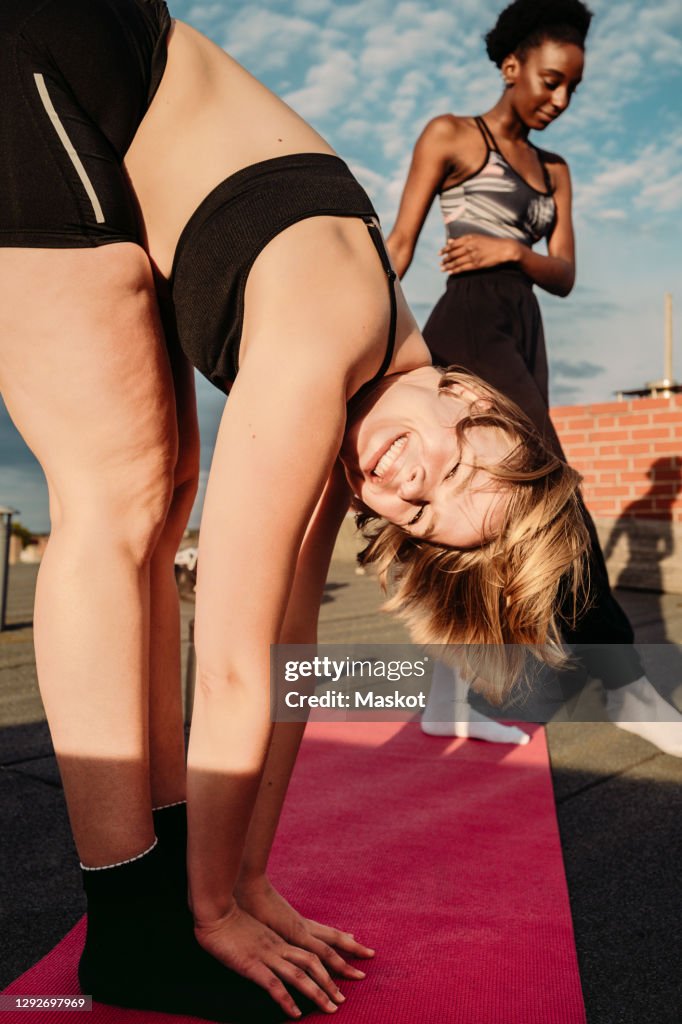 Portrait of smiling woman exercising with female friend on rooftop