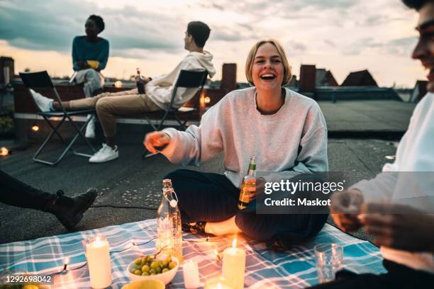 cheerful female with friends enjoying on building terrace during sunset - twilight picnic stock pictures, royalty-free photos & images