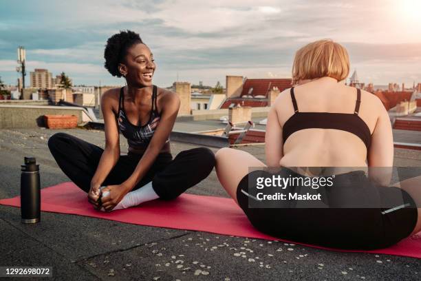 smiling female friends exercising on rooftop - sunrise yoga stock pictures, royalty-free photos & images