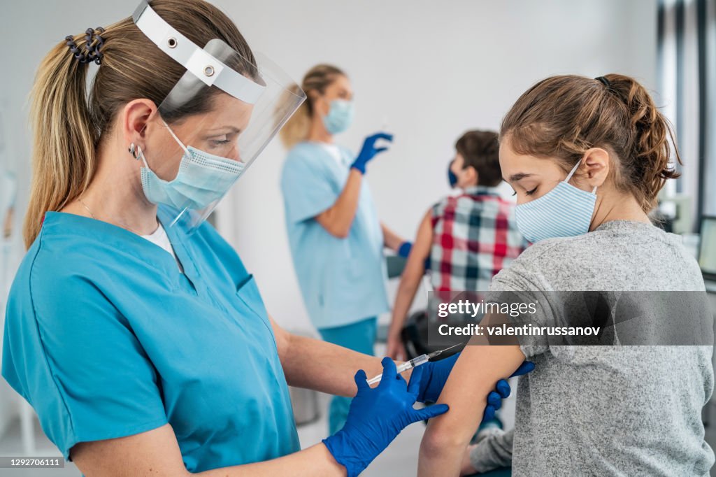Doctor vaccinating girl. Injecting COVID-19 vaccine into patient's arm