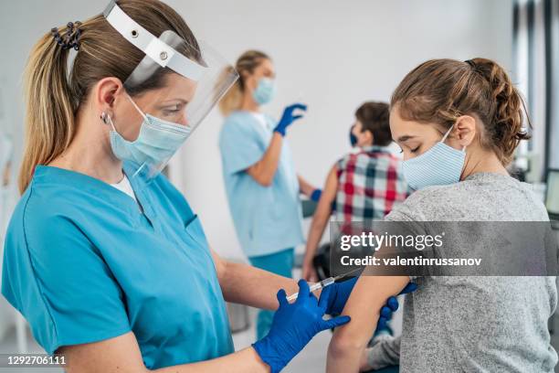 doctor vaccinating girl. injecting covid-19 vaccine into patient's arm - girl medical exam stock pictures, royalty-free photos & images