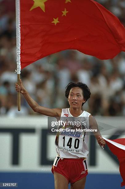 Junxia Wang of China carries two Chinese flags on a lap of honour after winning the 10 000 metres event at the World Championships in Stuttgart,...