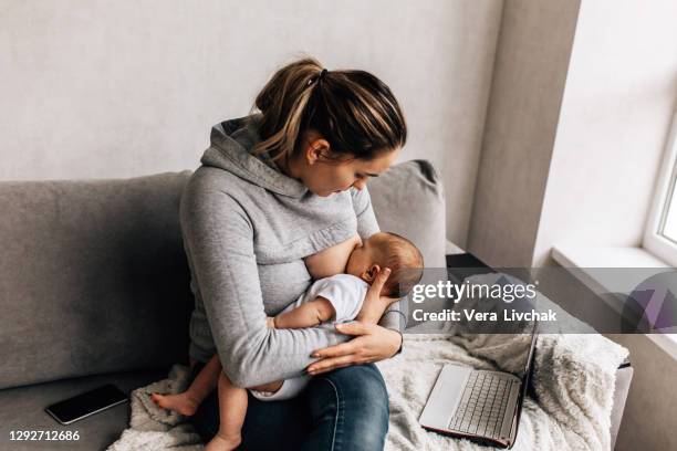 young woman breastfeeding her baby in bedroom - eltern stock pictures, royalty-free photos & images