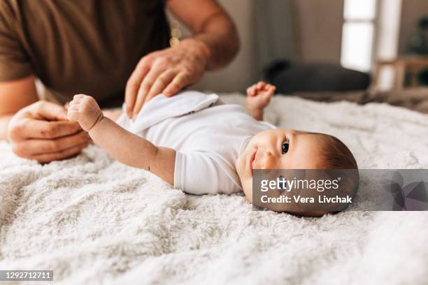 middle age caucasian father changing diaper for newborn baby daughter. male man parent taking care of child at home alone. authentic lifestyle candid moment. single dad family life concept. - nappy change stock pictures, royalty-free photos & images