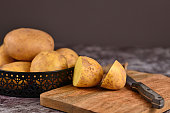 Cutting raw potato with peel on wooden cutting board