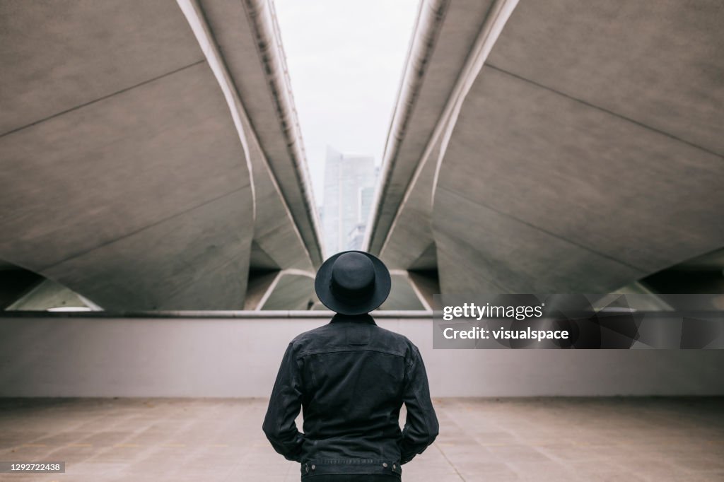 Rear view of man standing under a bridge