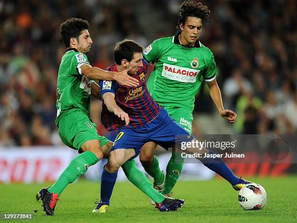 Lionel Messi of FC Barcelona duels for the ball with Alvaro Gonzalez and Edu Bedia of Racing Santander reacts during the la Liga match between FC...