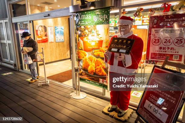 Man holding a Christmas meal box leaves a KFC restaurant on December 23, 2020 in Tokyo, Japan. KFC at Christmas has become something of a tradition...