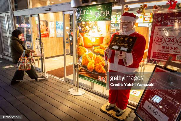 Woman sanitize her hand in front of a KFC restaurant on December 23, 2020 in Tokyo, Japan. KFC at Christmas has become something of a tradition in...