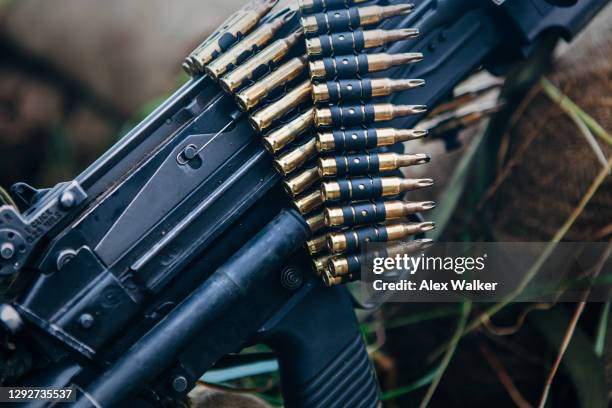 a belt of blank training bullet rounds resting on top of an light machine gun - maschinengewehr stock-fotos und bilder