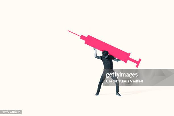 young man carrying large pink injection - carrying photos et images de collection