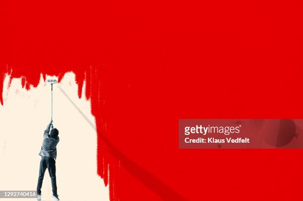 man erasing red covid-19 virus with paint roller - creativity foto e immagini stock