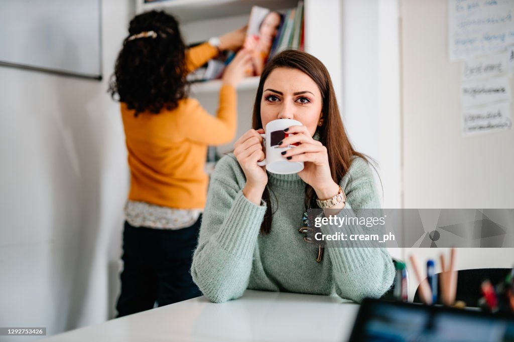 Woman a teacher drinking coffee in the staffroom