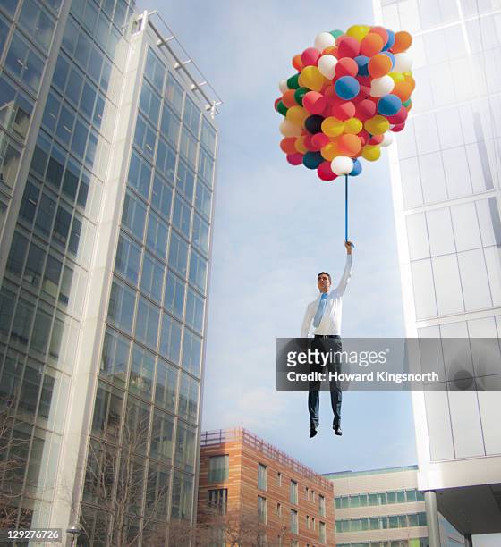 man lifted into sky by huge bunch of balloons - bunch imagens e fotografias de stock