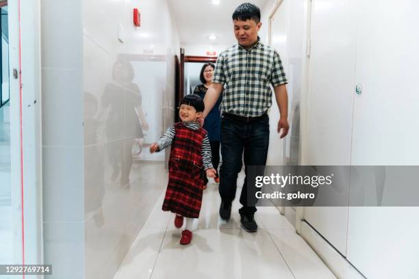 young chinese family with one daughter in staircase of new residential building - middle class stock pictures, royalty-free photos & images