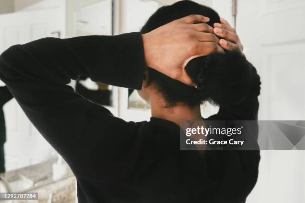 woman puts her hair into a bun - hair elastic stock pictures, royalty-free photos & images