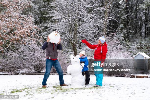 a caucasian family with one child is making a snowman. mom, dad and daughter are 5 years old. - 50 years old man imagens e fotografias de stock