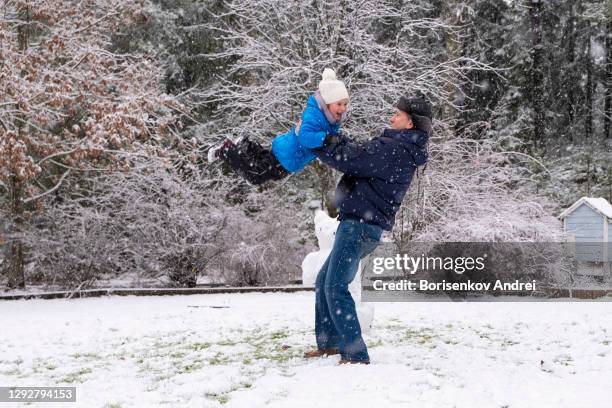 a caucasian man holds a 5-year-old girl in his arms and throws her up. winter joyful weekend with family. - grandfather child snow winter stock pictures, royalty-free photos & images