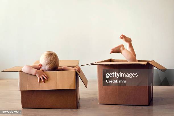 two babies playing in cardboard boxes - zwilling stock-fotos und bilder