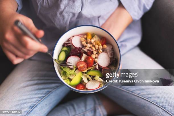 green vegan breakfast meal in bowl with spinach, arugula, avocado, seeds and sprouts. girl in leggins holding plate with hands visible, top view. clean eating, dieting, vegan food concept - pratos vegetarianos imagens e fotografias de stock