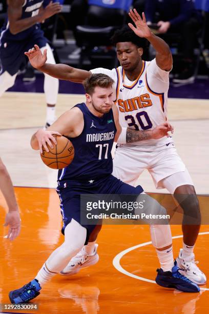 Luka Doncic of the Dallas Mavericks handles the ball guarded by Damian Jones of the Phoenix Suns during the first half of the NBA game at PHX Arena...