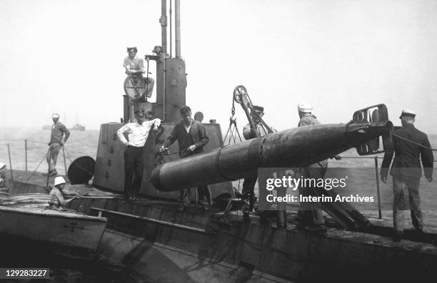 Group of sailors stand on the top deck of a submarine as they recover a torpedo from the ocean, 1918.