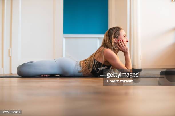 donna sorridente sdraiata sul davanti con le gambe in posizione loto, allenamento a casa yoga - china foto e immagini stock
