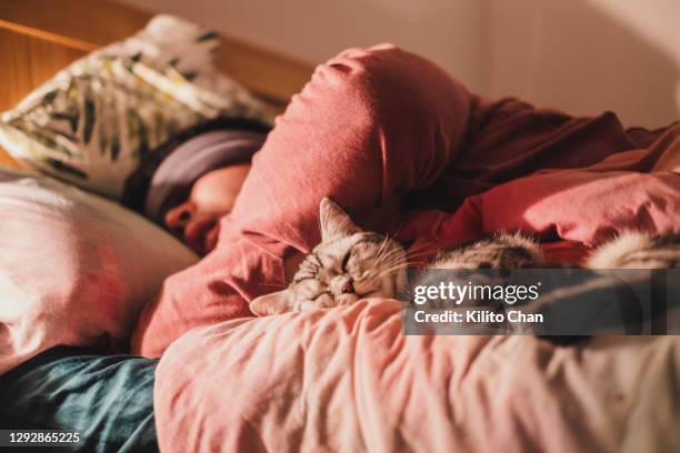 asian man wearing sleep mask, sleeping with his cat - bed sleep stockfoto's en -beelden