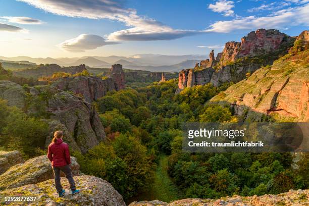 woman looking at belogradchik rocks at sunrise - bulgarije stockfoto's en -beelden