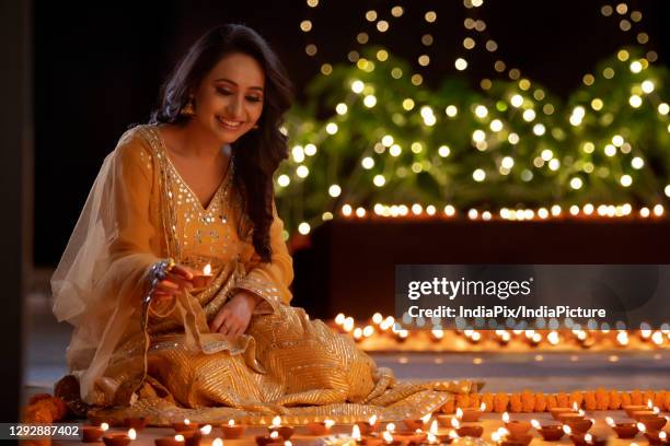 woman decorating her house with diyas on the occasion of diwali - diya oil lamp fotografías e imágenes de stock