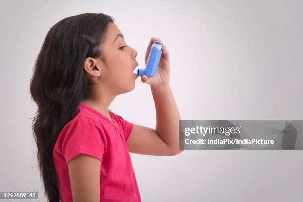 young asthma patient taking an inhaler. (children) - asthma inhaler stock pictures, royalty-free photos & images