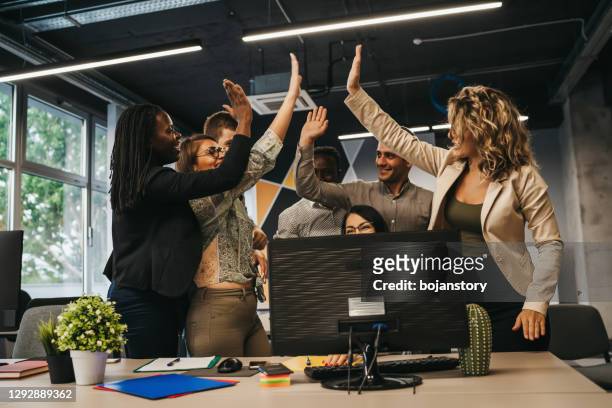 happy multinational coworkers giving high five celebrating great teamwork result - business high five stock pictures, royalty-free photos & images