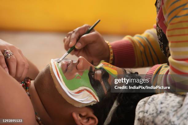 kathakali dancer lying on the chatai and his makeup artist giving shape to the chutty on his face. - kathakali dancing fotografías e imágenes de stock