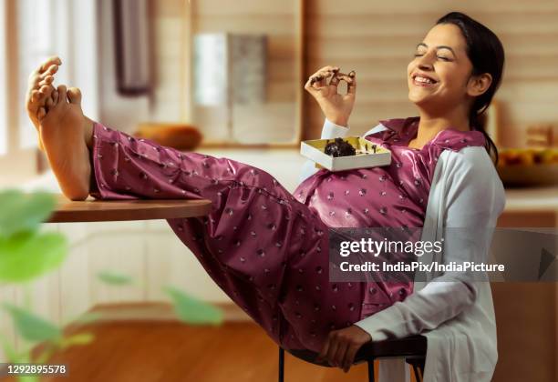 pregnant woman smiling and eating a chocolate cake. - chocolate cake stockfoto's en -beelden