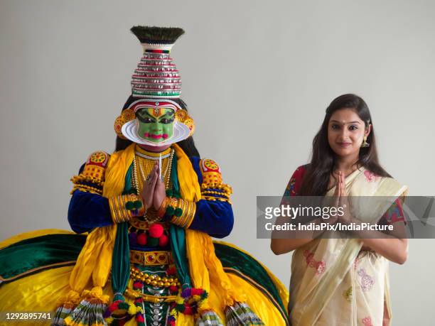 kathakali dancer and a young woman standing together with their hands folded. - kathakali dancing stock-fotos und bilder