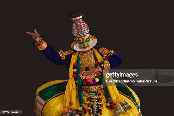 kathakali dancer dancing in front of a dark background. - kathakali dancing stockfoto's en -beelden