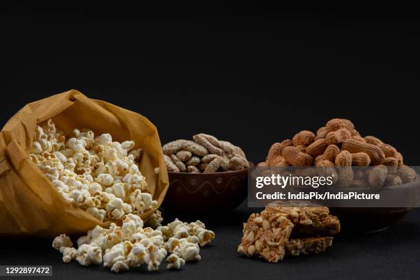 popcorns in a brown bag kept alongside chikki and bowls of rewari and groundnuts. - lohri festival stock-fotos und bilder