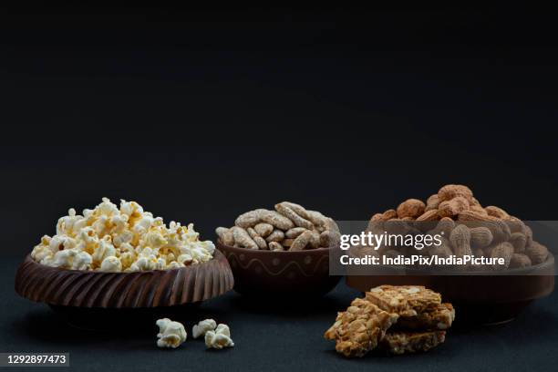 chikki kept alongside bowls of rewari, groundnuts and popcorns. - lohri festival imagens e fotografias de stock