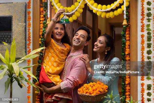 portrait of a happy family looking at fancy lantern and posing in front of decorated entrance - diwali decoration stock pictures, royalty-free photos & images