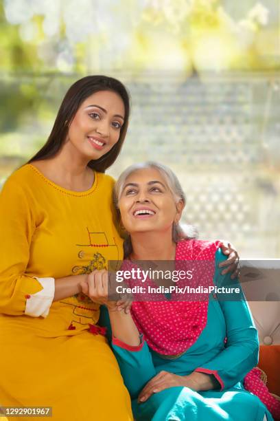 portrait of mother and daughter sitting in living room - mother in law stock pictures, royalty-free photos & images