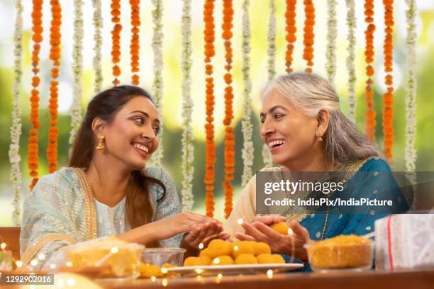 mother in law teaching daughter in law how to make ladoo on the occasion of diwali celebration - diwali greetings stock pictures, royalty-free photos & images