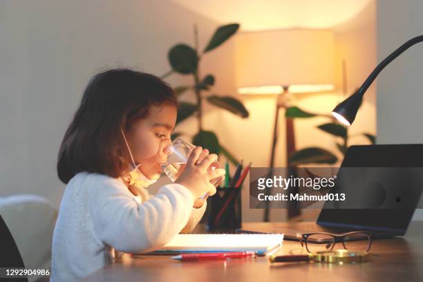 chica linda beber un vaso de agua mientras estudia - estudiando flexo fotografías e imágenes de stock