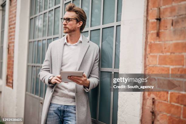 handsome gentleman using tablet on the street - masculinidade moderna imagens e fotografias de stock